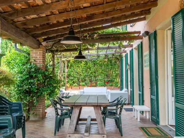 An outdoor patio with a wooden pergola, green chairs, a table, and a white sofa. - Ca' del Vento by Interhome (Oltrepò Pavese)