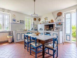 A kitchen with a central island, blue chairs, and a tiled backsplash. - Ca' del Vento by Interhome (Oltrepò Pavese)