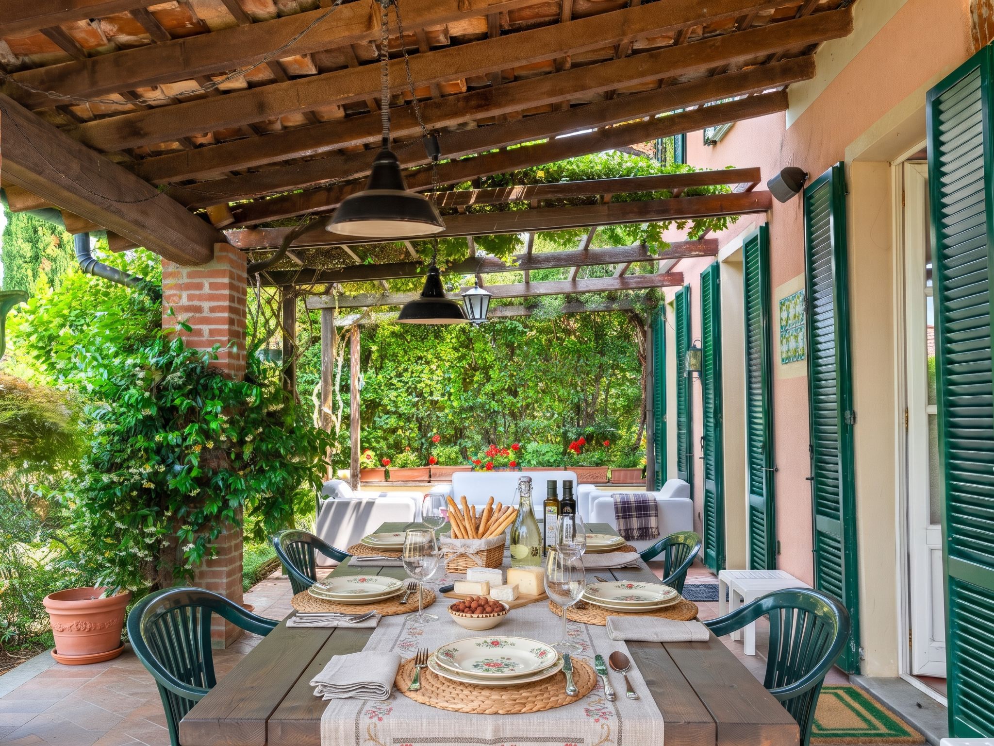 An outdoor dining area with a pergola, tables set for two, and a view of a garden.