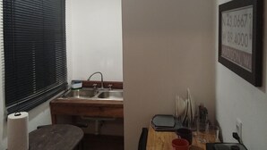 A compact kitchen with a sink, a wooden table, and a framed sign on the wall. - DGM Lofts MTY F (Monterrey)