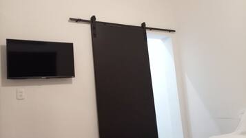 Un dormitorio con cama, televisor de pantalla plana en la pared y puerta corredera.