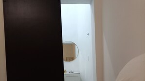 A bedroom with a bed, a white wall, a round mirror, and a white door. - DGM Lofts MTY F (Monterrey)