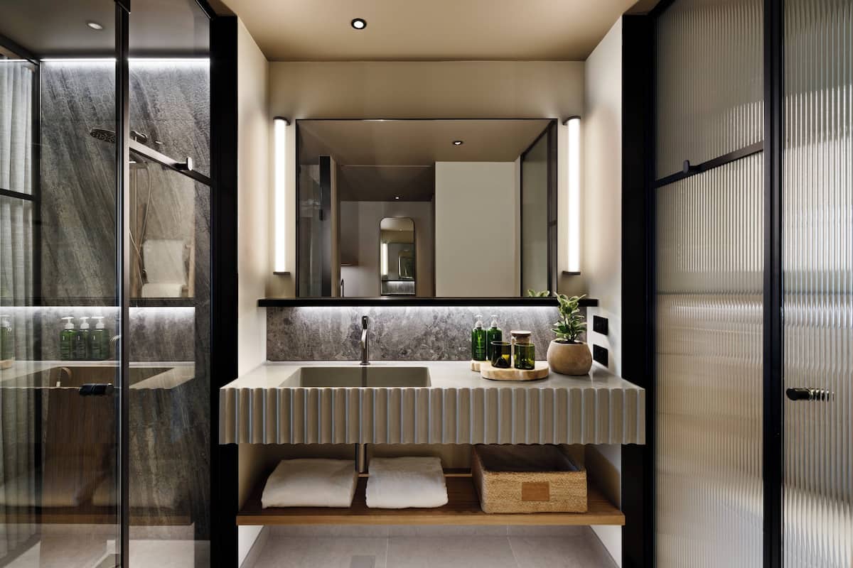 Un baño moderno con cabina de ducha de vidrio, encimera de mármol y un espejo grande.