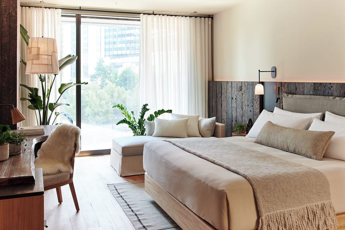 Una habitación de hotel moderna con una cama grande, un escritorio y vistas a la ciudad.
