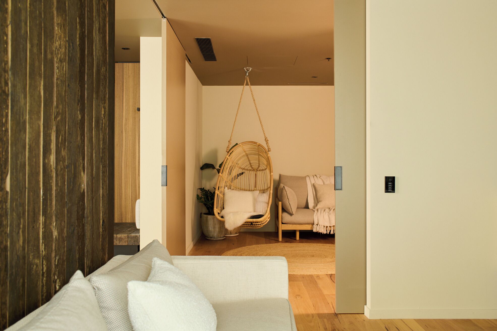 A modern interior with a hanging chair, a sofa, and a small table with a plant.