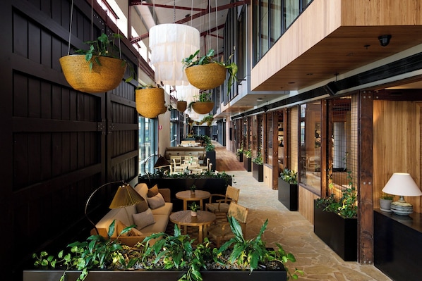 Un hall d’hôtel moderne, agrémenté de suspensions florales, de coins salon et d’un comptoir d’accueil.