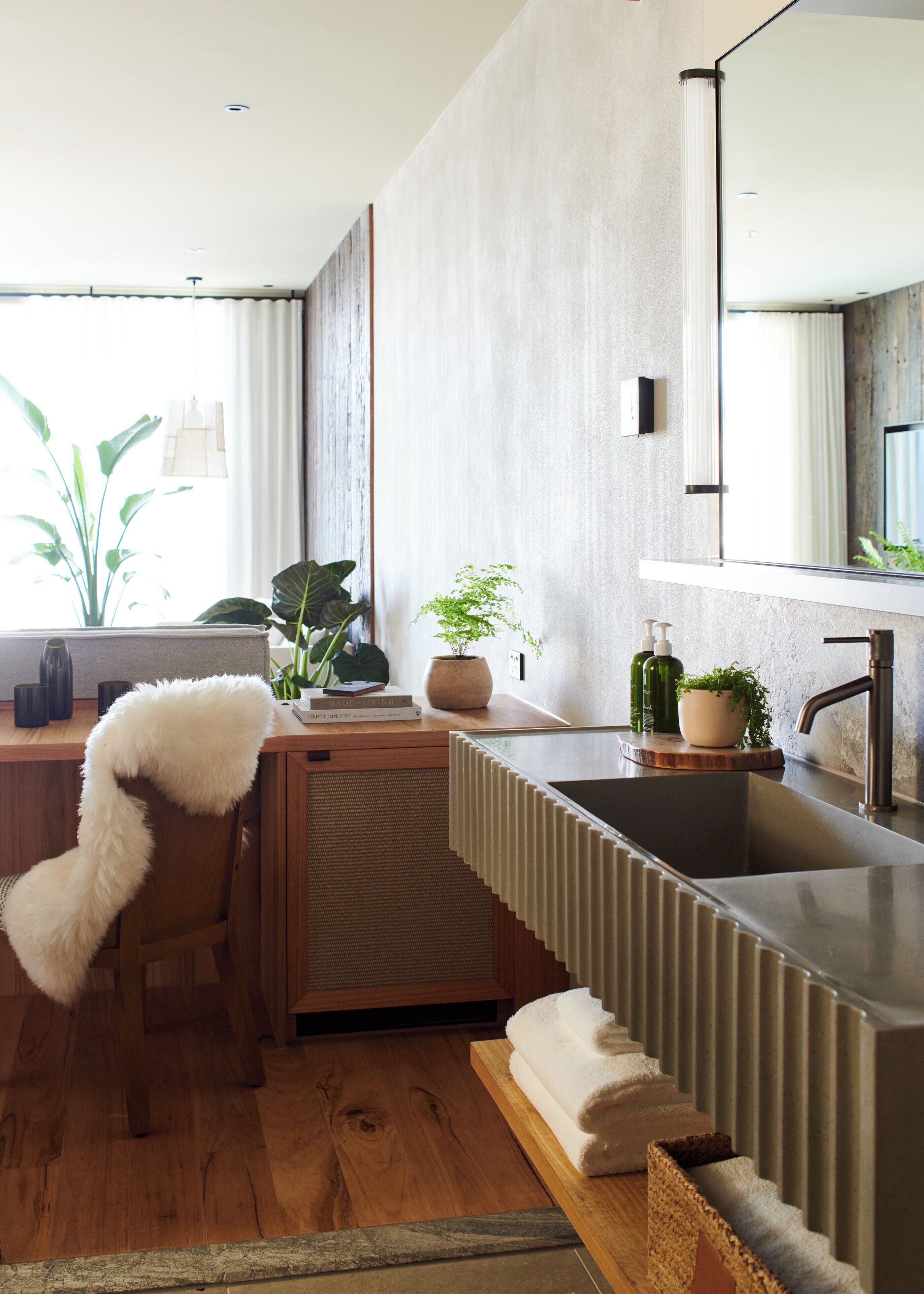 Ein modernes Badezimmer mit einem Holzwaschtisch, einem großen Spiegel und einem integriertem Waschbecken.