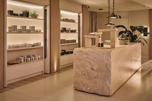 Un interno moderno con una reception in marmo, scaffali con articoli da toilette e una pianta in vaso.