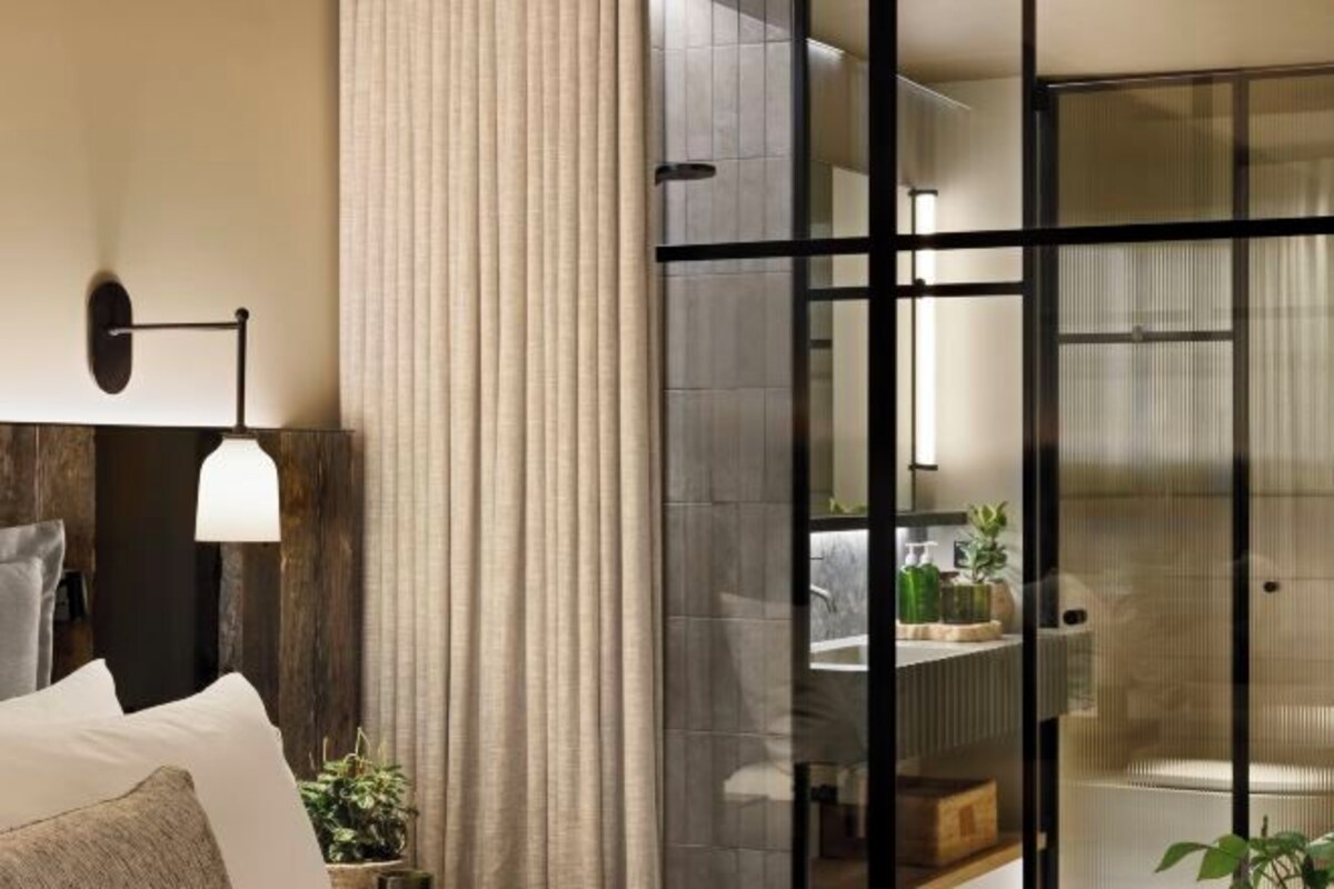 Un baño moderno con cabina de ducha de vidrio, un perchero y una zona de lavamanos visible.