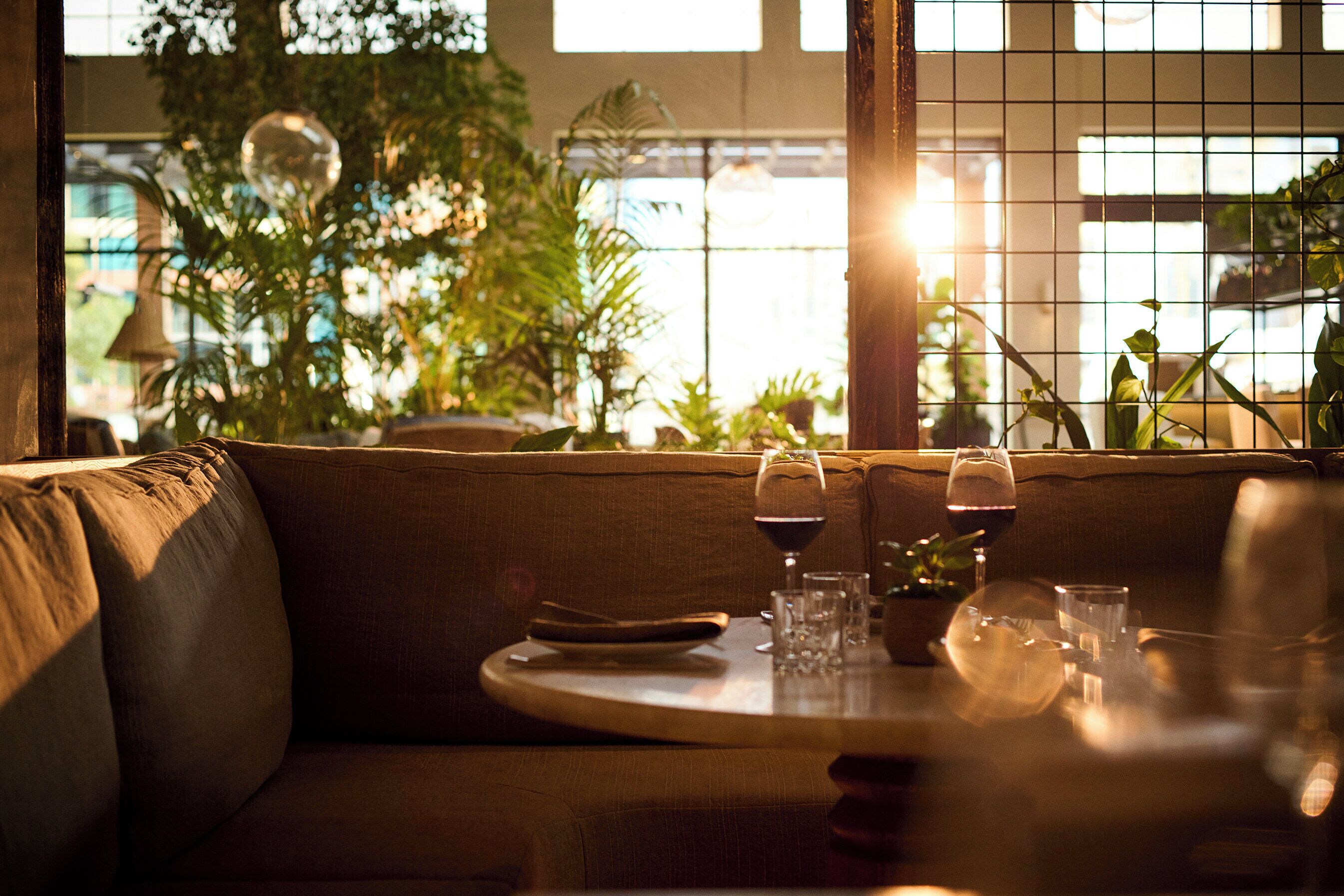 A cozy indoor setting with a round table set for dining, surrounded by a cushioned sofa.