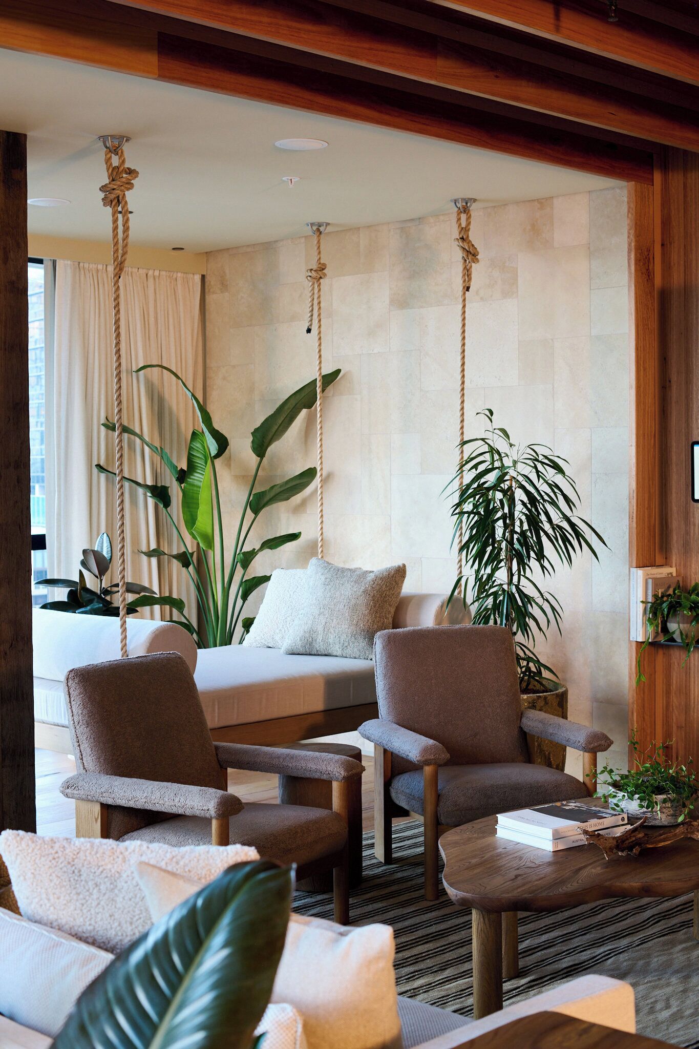 Une pièce comprenant un lit, deux fauteuils, une table basse et de grandes plantes.