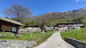 A rural setting with stone buildings, a clear path, and a mountain in the background. - Casa Kiwi by Interhome (Cercino)