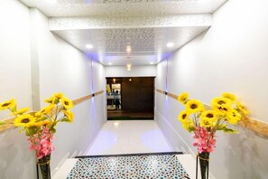 Un pasillo con piso estampado, paredes blancas y dos jarrones con girasoles.