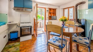 Une cuisine compacte équipée d’une cuisinière à gaz, d’un meuble bleu et d’un coin repas avec une table et des chaises en bois.