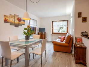 Una sala de estar moderna con una mesa de comedor de vidrio, sofá de cuero y televisor.