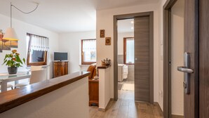 Una cuina moderna amb taulell de fusta, zona de menjador amb una cadira i vista cap al saló.
