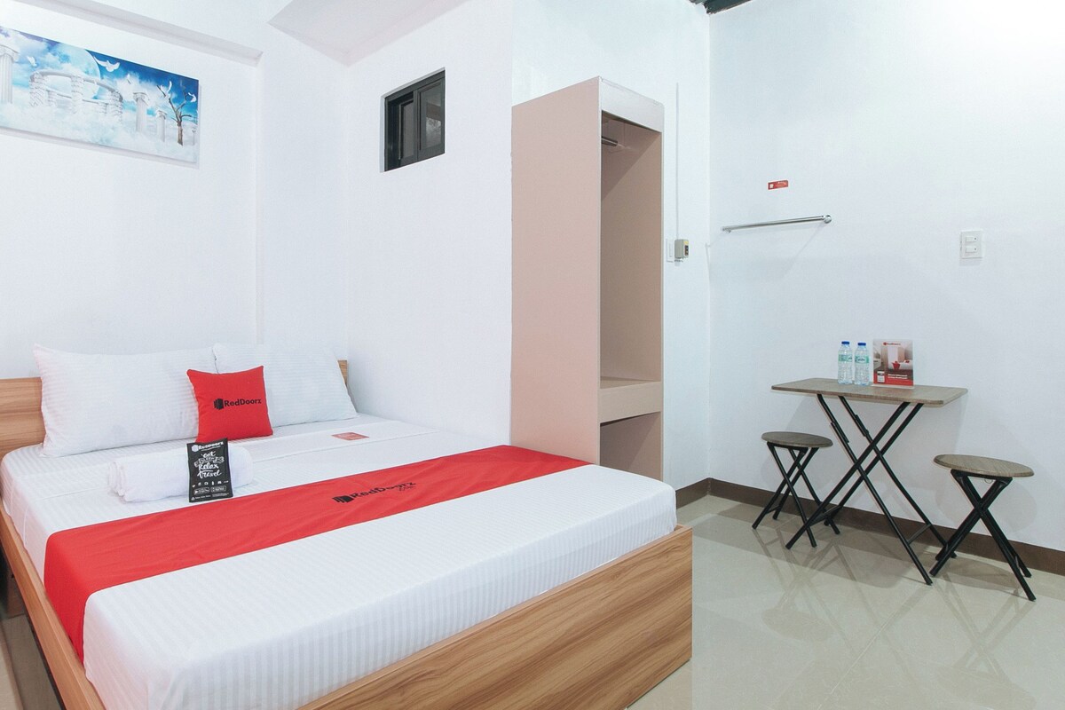 A hotel room with a bed, a small table with water bottles, a painting on the wall, and a closet.