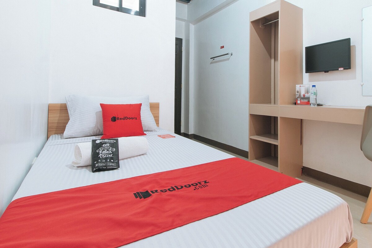 Een hotelkamer met een bed, een bureau, een stoel, een televisie en een schilderij aan de muur.