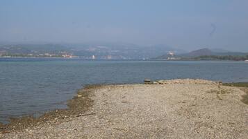 Escape to a serene lakeside haven with a pebble-strewn shore and breathtaking views of the surrounding town and hill.