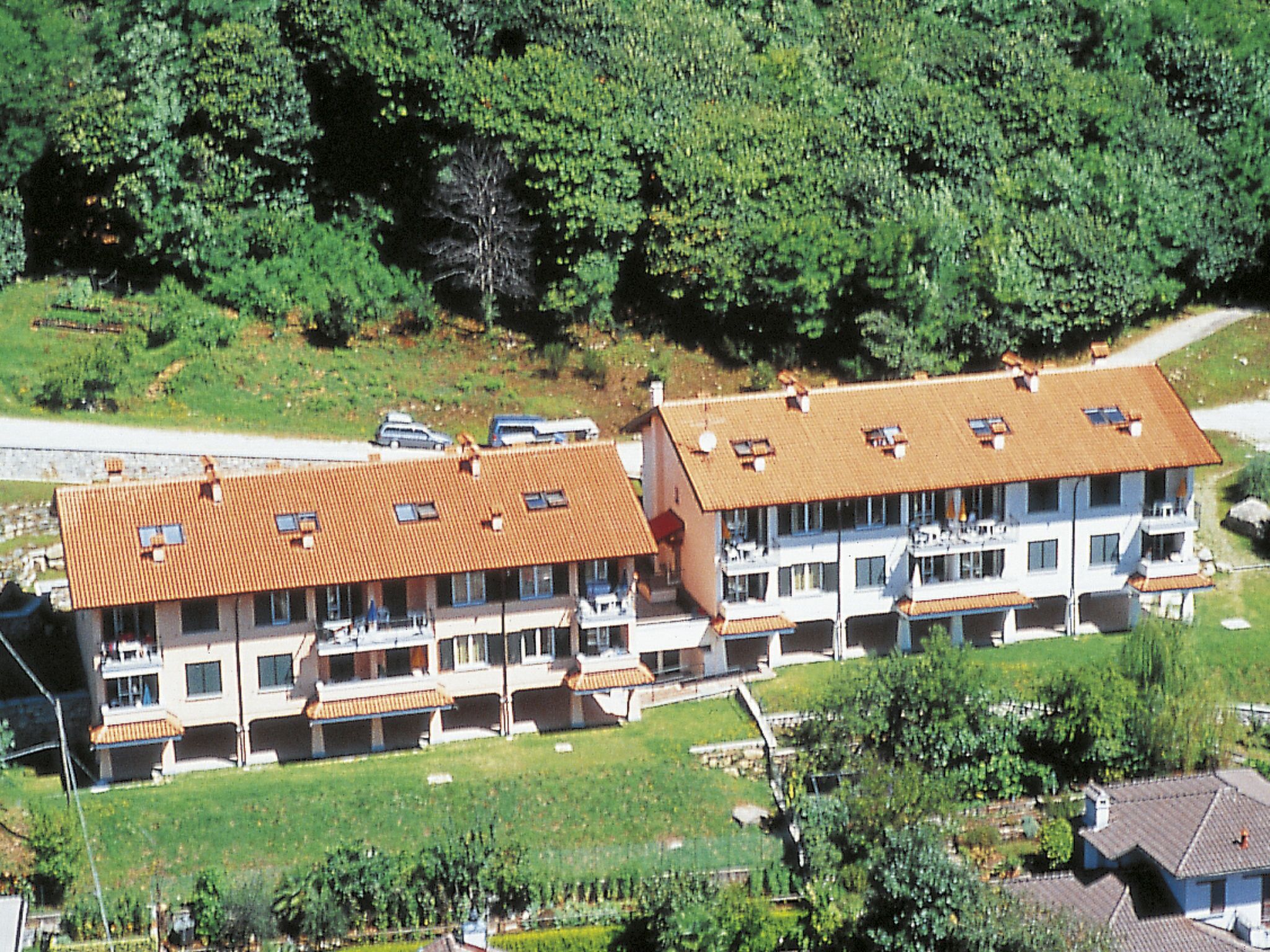 A multi-story building with a tiled roof, balconies, and a garden area.