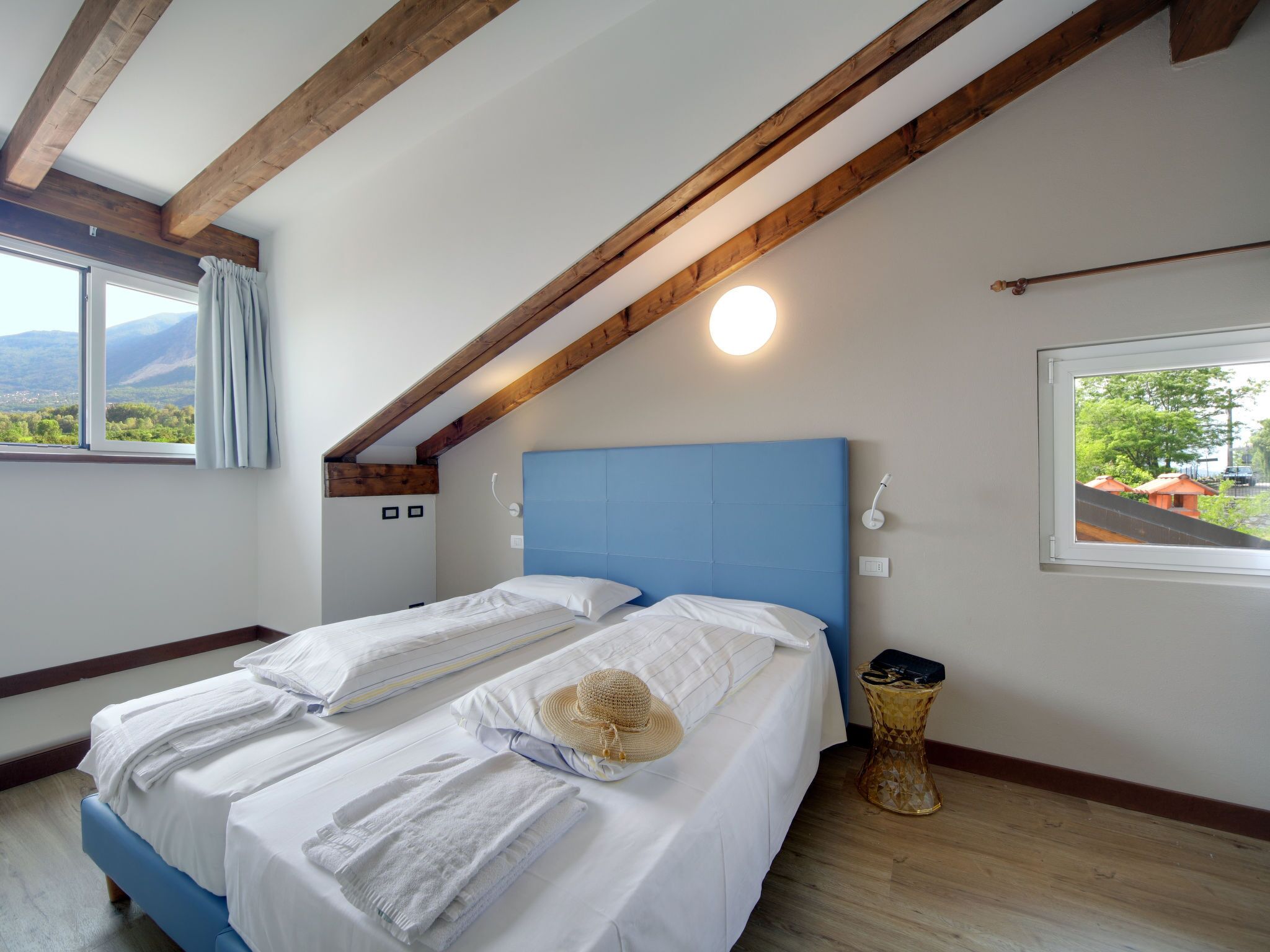 Ein Schlafzimmer mit Bett, Fenster, Nachttisch und Lampe.