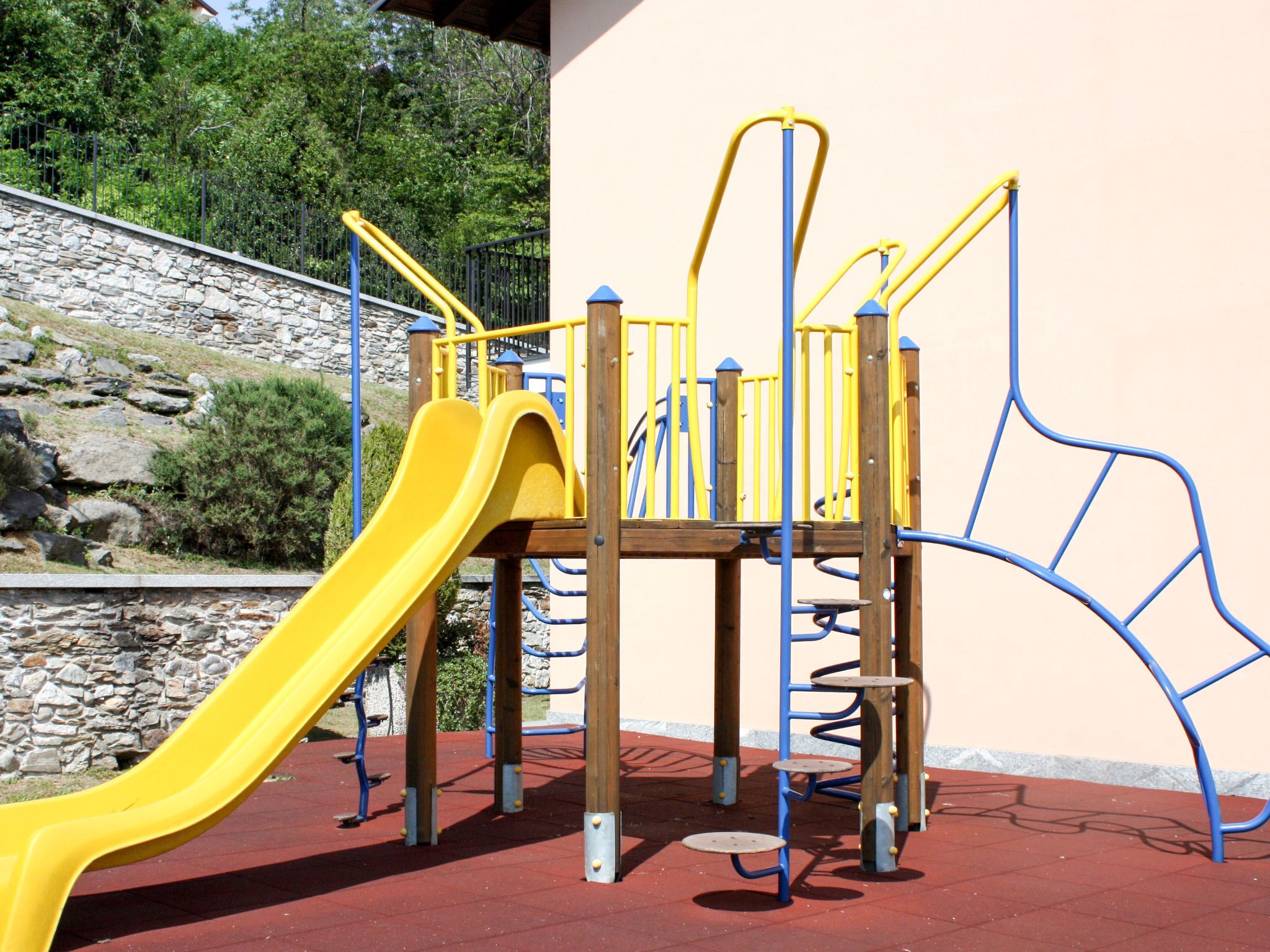 Une aire de jeux avec un toboggan jaune et des structures d’escalade.