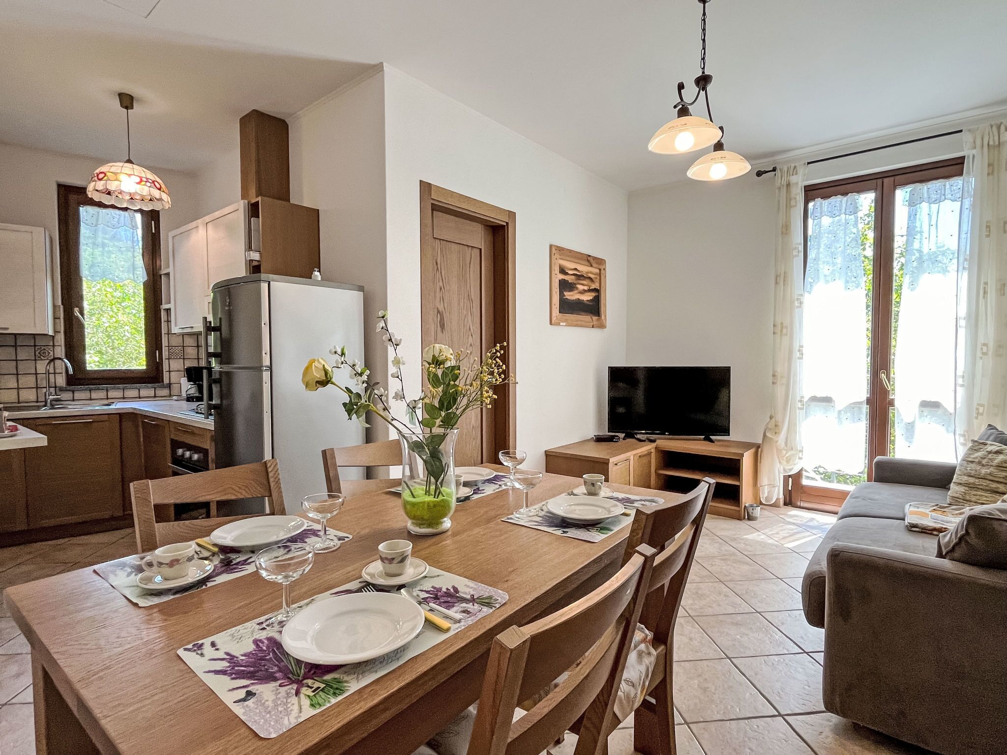 Una cocina moderna con refrigerador, estufa y comedor listo para una comida.