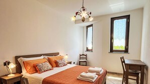 Een keurig opgemaakt slaapkamer met een bed, nachtkastjes, een bureau en een stoel.