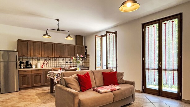 Een ruime woonkamer met een bank, een eettafel en een keuken op de achtergrond.
