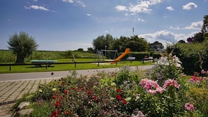 Um parque com parquinho, mesa para piquenique e flores.