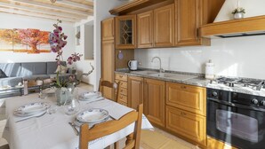 A modern kitchen with wooden cabinets, a gas stove, and a dining area with a table set for two.