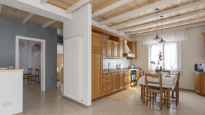 A spacious kitchen with wooden cabinets, a dining area with a table and chairs, and a high ceiling with exposed beams.
