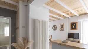 A modern kitchen with a wooden countertop, a white radiator, and a dining area with a chair and table.
