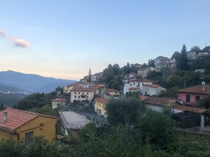 Un village perché sur une colline, avec des bâtiments traditionnels, une église imposante et une vue sur les montagnes lointaines.