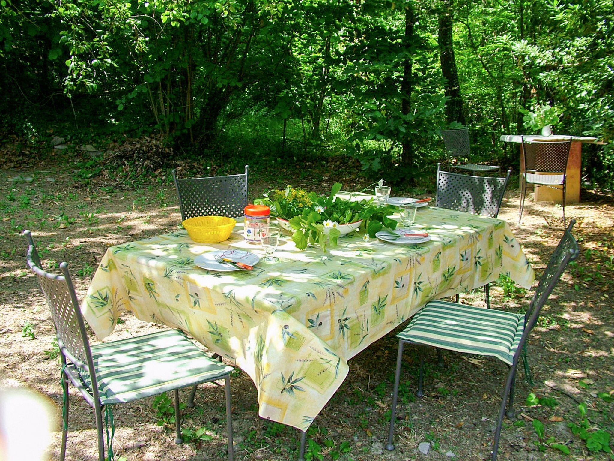 An outdoor dining area with a table set for two, surrounded by metal chairs.