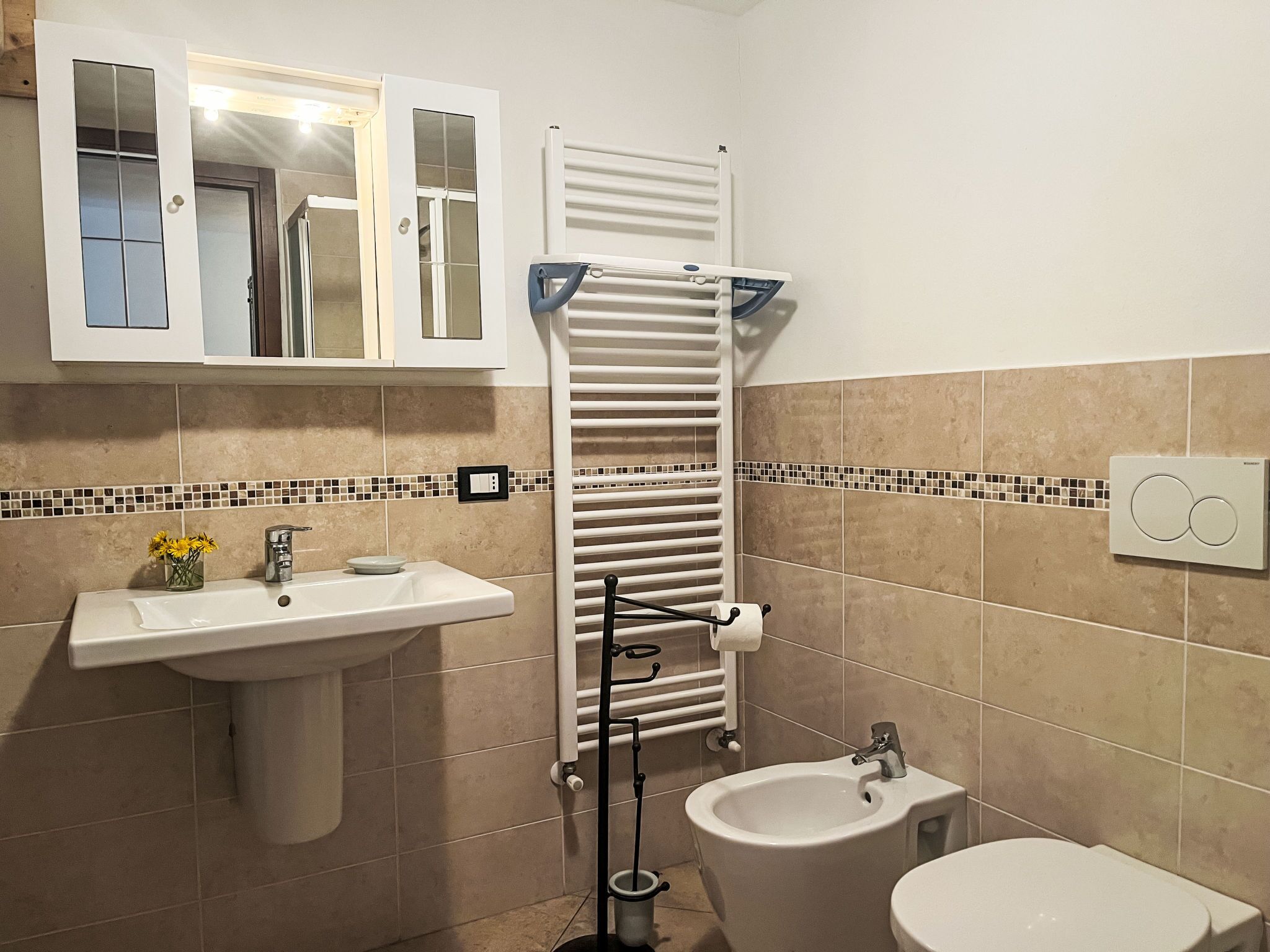 A bathroom with a sink, bidet, toilet, towel rack, and a mirror above the sink.