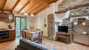 A cozy kitchen with wooden beams, a stone fireplace, and a dining area with a table set for four. - Ca' da Ciassa + Prima Porta (VLO132) by Interhome (Valloria)