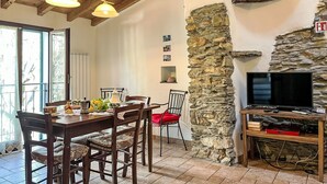 A dining area with a wooden table, chairs, and a stone wall. - Ca' da Prima Porta (VLO131) by Interhome (Valloria)