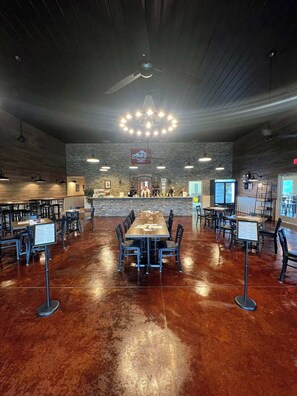 A spacious dining area with multiple tables and chairs, a central bar area, and a ceiling fan.