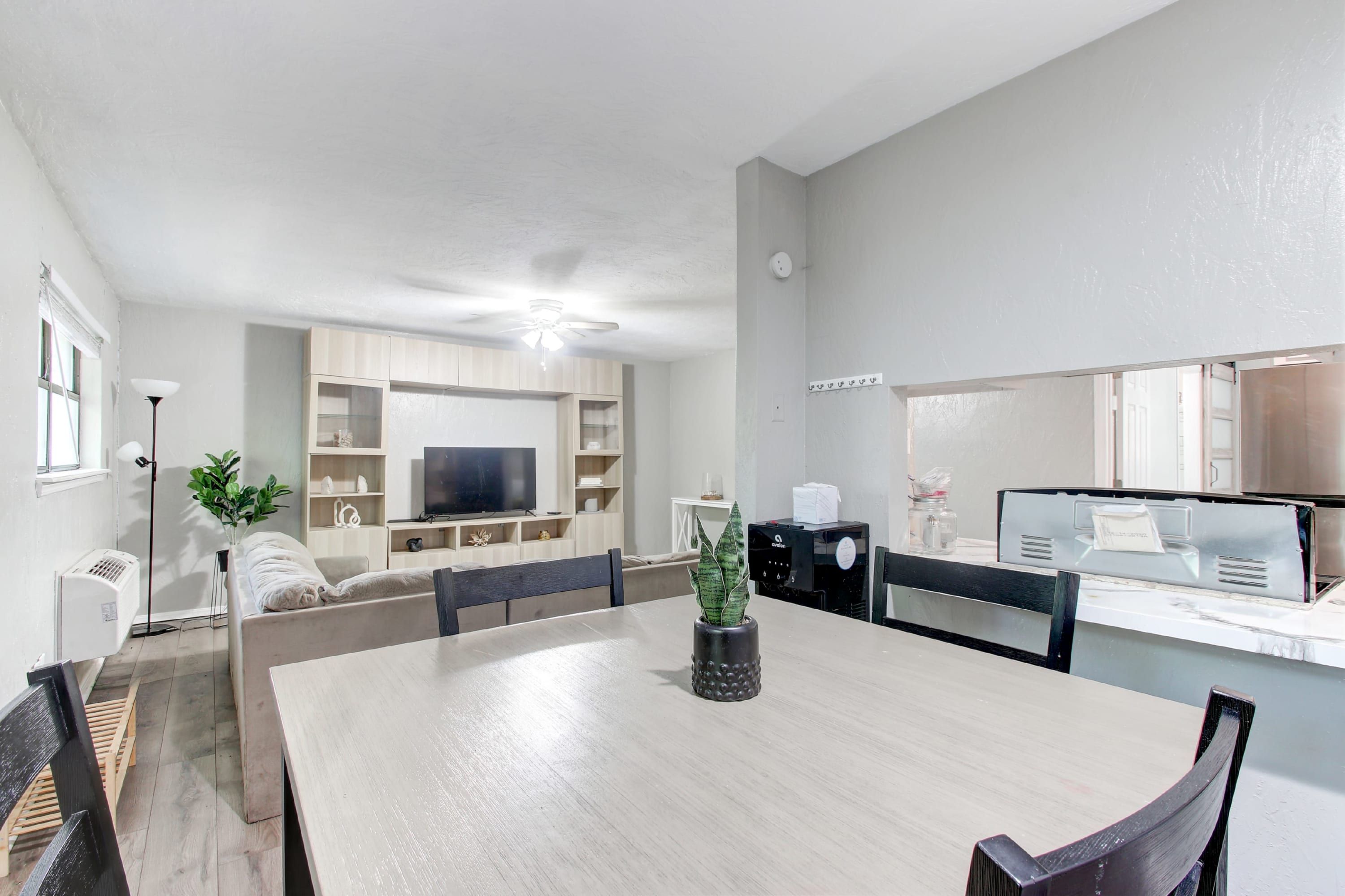 Un salon moderne comprenant une table à manger, des chaises, un canapé, un téléviseur et un coin cuisine équipé d’un four à micro-ondes et d’un grille-pain.