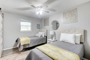 A bedroom with two beds, a ceiling fan, a window, and a wall-mounted mirror. - Cozy 2 Bedroom Apartment in Lawton Near Downtown (Lawton)