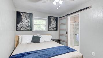 Une chambre à coucher avec un lit, un ventilateur de plafond et deux tableaux représentant un léopard.