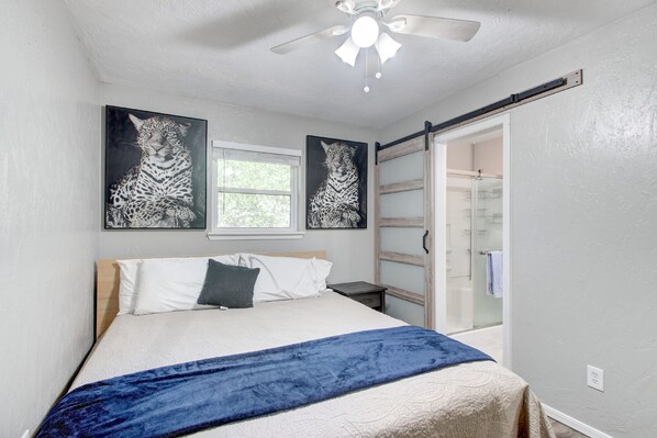 A bedroom with a bed, a ceiling fan, and two framed pictures of a leopard.