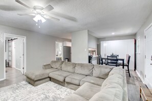 A living room with a sectional sofa, a ceiling fan, and a dining area in the background. - Cozy 2 Bedroom Apartment in Lawton Near Downtown (Lawton)