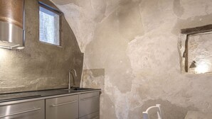 Une cuisine dotée d’un évier en acier inoxydable, d’une fenêtre et d’un mur en pierre rustique.