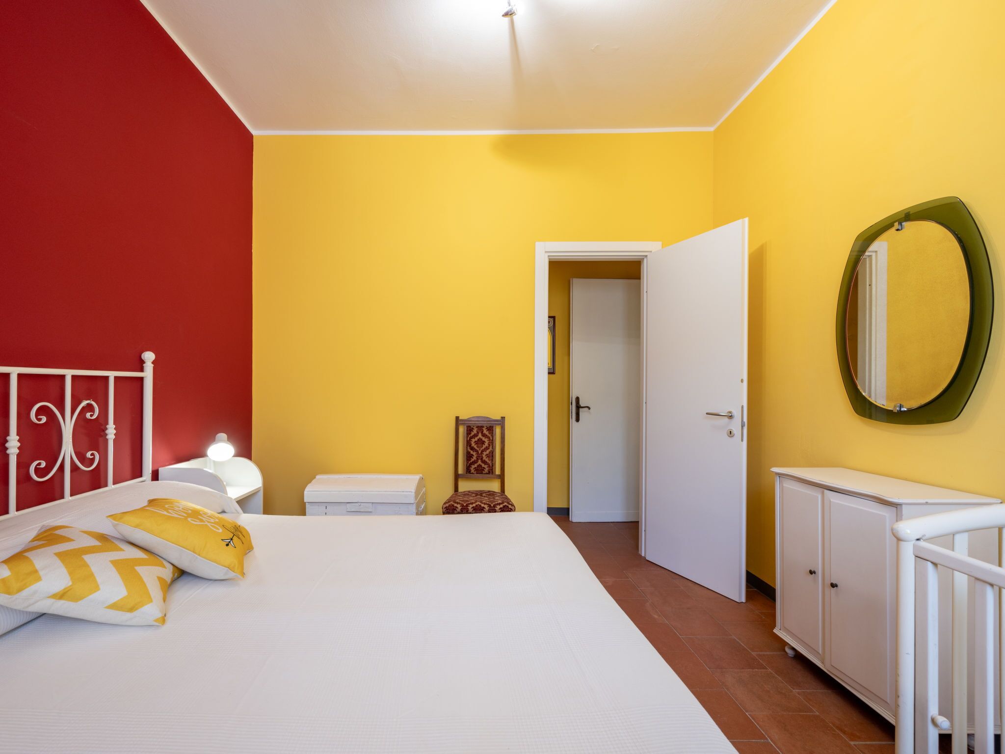 Ein Schlafzimmer mit Bett, Nachttisch, Kleiderschrank und Spiegel an der Wand.