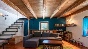 Uma sala de estar acolhedora com escada de madeira, sofá seccional, mesa de centro e estante de livros.