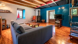 Uma sala de estar acolhedora com teto de madeira, parede azul decorativa, lareira e televisão.