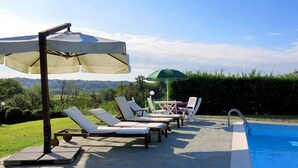A poolside area with lounge chairs and umbrellas, a clear view of the landscape, and a swimming pool. - Il Marchese del Grillo by Interhome (Capriglio)