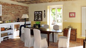 A dining area with a brick ceiling, a wooden table, and chairs. There is a window with a view of greenery outside. - Il Marchese del Grillo by Interhome (Capriglio)